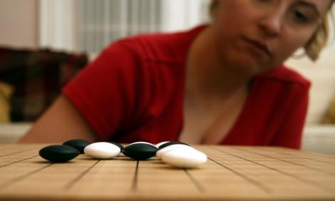 Woman considers a play in a Go board