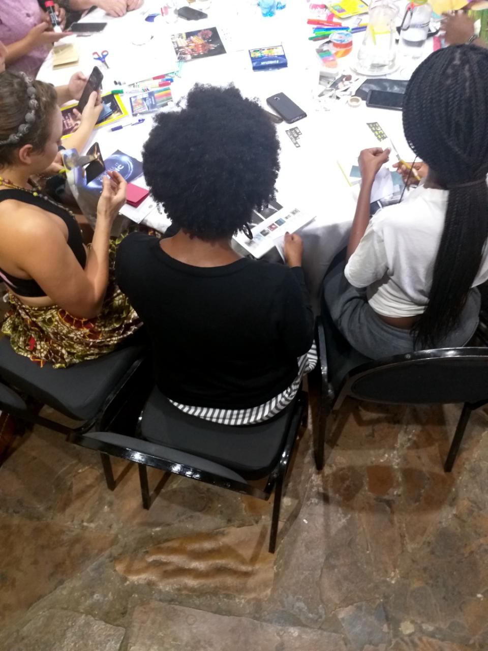 A group of African women making collage art around a table